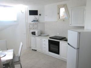 a kitchen with white cabinets and a white refrigerator at Sardinia Yellow House in Solanas