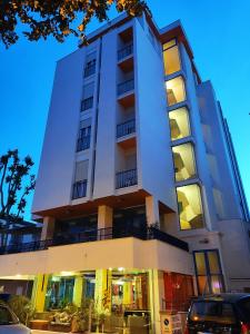 a tall white building with a car parked in front of it at Hotel Senior in Cattolica