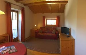 ein Wohnzimmer mit einem Sofa und einem TV in der Unterkunft Lafreiderhof in Kastelruth