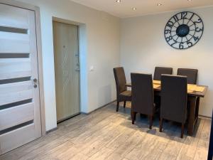 ein Esszimmer mit Tisch und Stühlen und einer Uhr in der Unterkunft Apatamentas Nidos centre in Nida