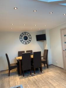ein Esszimmer mit Tisch und Stühlen und einer Uhr in der Unterkunft Apatamentas Nidos centre in Nida + 5 Fotos
