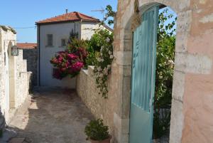 an alley with a blue door and a building with flowers at Sergios Village House in Chania