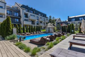 a hotel with a swimming pool and chairs and a building at Neringos apartamentai in Palanga