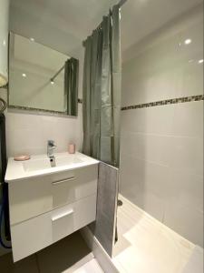 uma casa de banho branca com um lavatório e um chuveiro em Joli studio rénové en bord de mer em Bormes-les-Mimosas