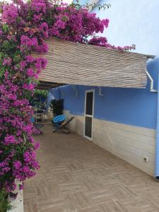 un edificio azul con flores púrpuras en él en Scala dei Turchi Beach house en Realmonte