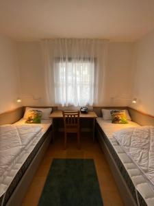 Habitación con 2 camas, mesa y ventana en Haus Lechbruck, en Lechbruck