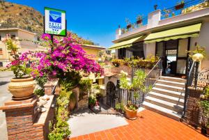 un edificio con fiori e piante di fronte di Hotel Condor a Taormina