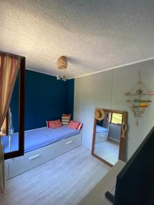 een kamer met een blauwe muur met een bank en een spiegel bij RIBES - Chalet Gîte au coeur de la nature in Sournia