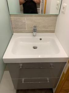 une personne prenant une photo d'un lavabo blanc dans la salle de bains dans l'établissement Le Prarion 2, aux Houches