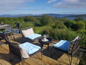 a deck with chairs and a table with a view of the water at Cois Farraige in Eadargóil +25 photos