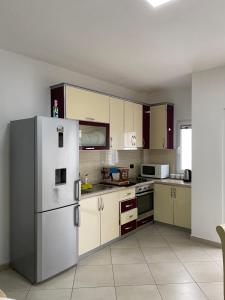 uma cozinha com armários brancos e um frigorífico em Super Apartment 100m2 2 sovrum em Shëngjin
