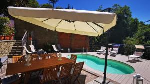 eine Terrasse mit einem Tisch und einem Sonnenschirm neben einem Pool in der Unterkunft Casa Bionzana in Pistoia