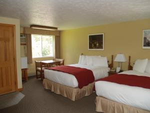 a hotel room with two beds and a table at Wilson Lake Inn in Wilton