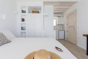 un dormitorio blanco con una cama con sombrero en Apartments enosis, Triton en Agia Anna Naxos