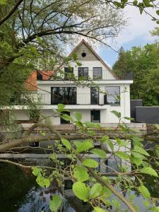 une maison blanche avec un étang en face de celle-ci dans l'établissement Vakantiehuis Ochtendgloren, à Turnhout