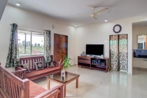 uma sala de estar com um sofá e uma televisão em Beautiful KP Sky View Bungalow em Mahabaleshwar