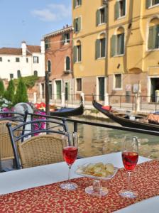 stół z dwoma kieliszkami wina i talerzem jedzenia w obiekcie Casa Burchielle w Wenecji
