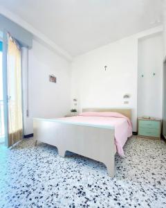 a bedroom with a white bed and a pink blanket at Hotel Dinarica in Marotta