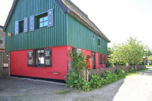 a green and red house with a fence at Tine in Ahrenshoop
