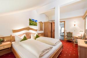 a bedroom with a large white bed and a desk at Gasthof Bären in Holzgau