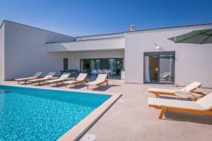 une piscine avec des chaises longues et une maison dans l'établissement Villa Mateo with heated pool, à Fažana