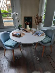 une table blanche avec deux chaises bleues dans une pièce dans l'établissement L'Oiseau De La Cathédrale - Calme - Jardin - Wifi, à Troyes