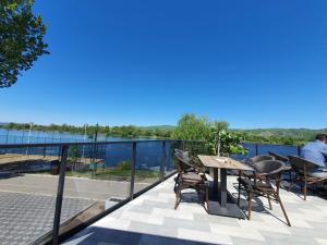 een patio met een tafel en stoelen en uitzicht op het water bij Andjelka A26 in Veliko Gradište