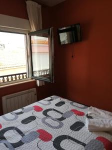 sypialnia z łóżkiem i telewizorem na ścianie w obiekcie O Encontro w mieście Fisterra