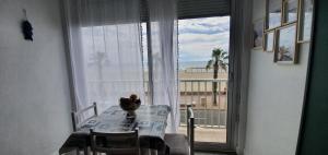 a dining room table with a view of a balcony at Studio les pied dans l eau ! in Canet-en-Roussillon