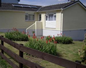 a fence in front of a house with flowers at Gara-Ni Bed & Breakfast in Fort William