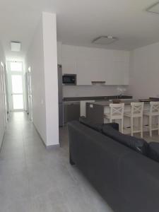 een woonkamer met een zwarte bank en een keuken bij Casa Blanca La Restinga in La Restinga