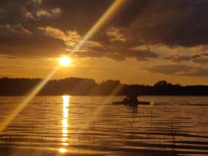 a person sitting on a boat in the water at sunset at Lämmijärve parvsaun in Värska