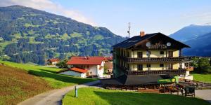 un edificio en una colina con montañas en el fondo en Pension Gemshorn, en Hainzenberg