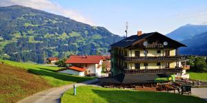 a building on a hill with mountains in the background at Pension Gemshorn in Hainzenberg