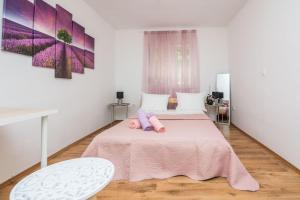 una camera da letto con un letto rosa con una bambola di Cosy apartments near the sport center and exercise park Višnjik - Zadar a Zara (Zadar)