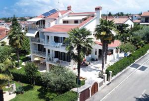 - une vue aérienne sur une grande maison blanche avec des palmiers dans l'établissement Apartments Mina, à Poreč