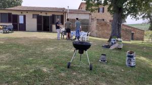 3 hommes debout dans une cour avec barbecue dans l'établissement Podere la Miniera, à Pienza