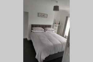 a bedroom with a bed with white sheets and pillows at place by the sea in Bridlington