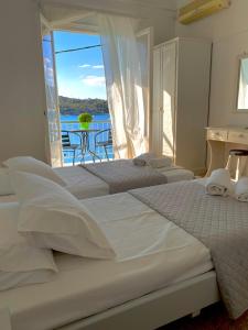 two beds in a bedroom with a view of the ocean at Studios Argyris in Poros