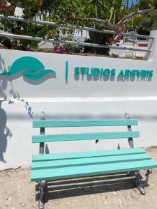 eine blaue Bank, die vor einem Schild sitzt in der Unterkunft Studios Argyris in Poros