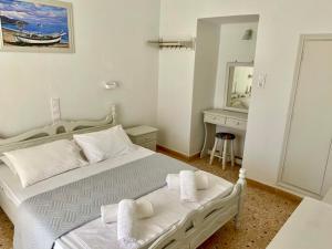 a white bedroom with a bed and a sink at Studios Argyris in Poros