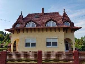 a house with a tiled roof on top of a fence at Henrietta Apartmanház in Zalakaros