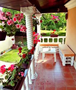 un porche con flores, un banco y una mesa en Vrdnik apartmani Sara, en Vrdnik