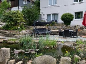 a garden with a pond with chairs and a swing at Hotel-Pension Teutonia in Braunlage