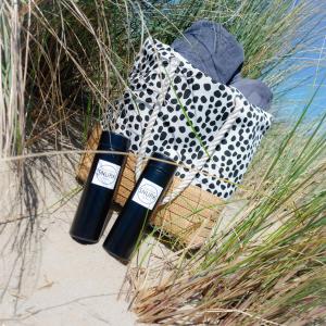 duas garrafas pretas sentadas na areia ao lado de um saco em Snurk Texel em Den Burg