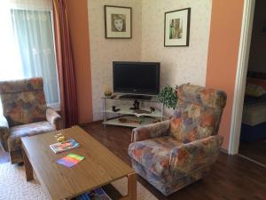 a living room with two chairs and a television at Frankie Holiday Apartment I. in Balatongyörök