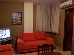 uma sala de estar com um sofá vermelho e uma televisão em Apartament Emiri Golem em Golem