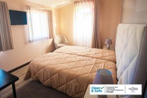 a hotel room with a bed and a chair at D. Irene Hostel in Lajes