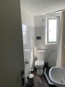 La salle de bains est pourvue de toilettes blanches et d'un lavabo. dans l'établissement Samothraki Akrogiali Rooms, à Samothráki