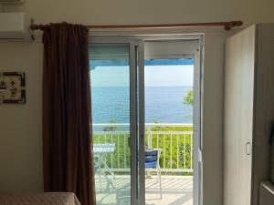 a room with a sliding glass door with a view of the ocean at Samothraki Akrogiali Rooms in Samothráki